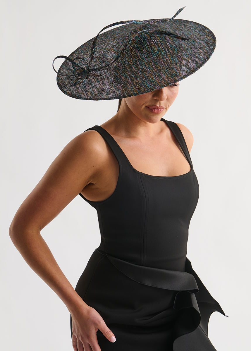 Woman wearing a black dress and decorative hat on a white background