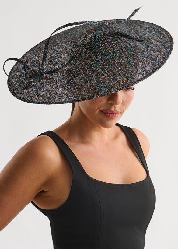 Woman wearing a black dress and decorative hat on a white background