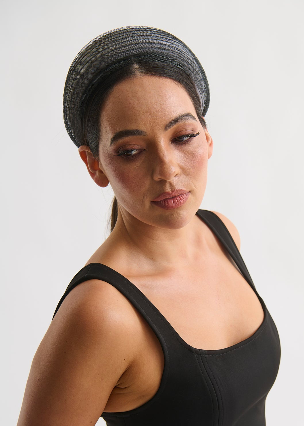 Woman wearing a black dress and headband against a white background