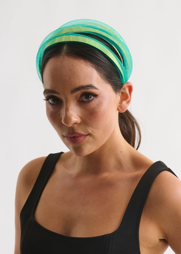 Woman wearing a black sleeveless top and green headband on a white background