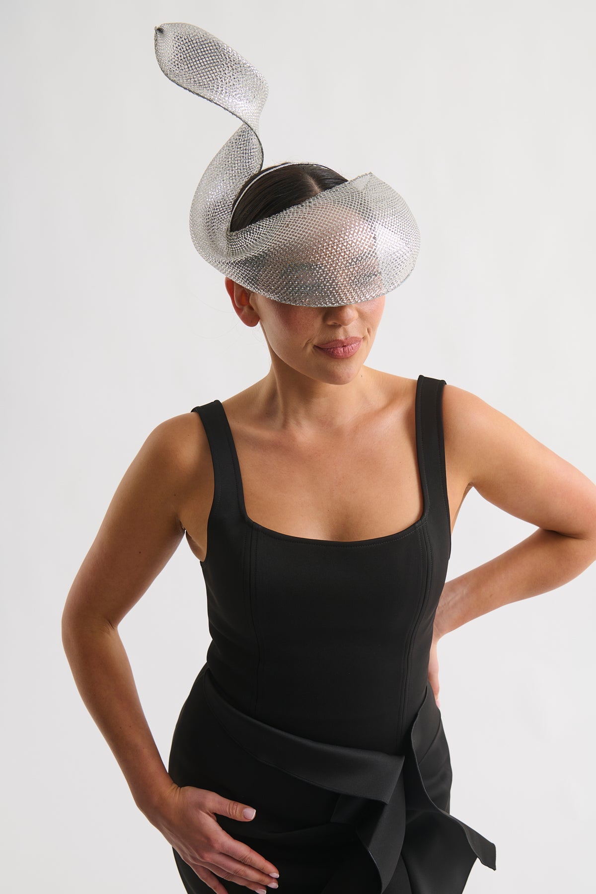 Woman wearing a silver swirl headpiece and a black dress against a white background