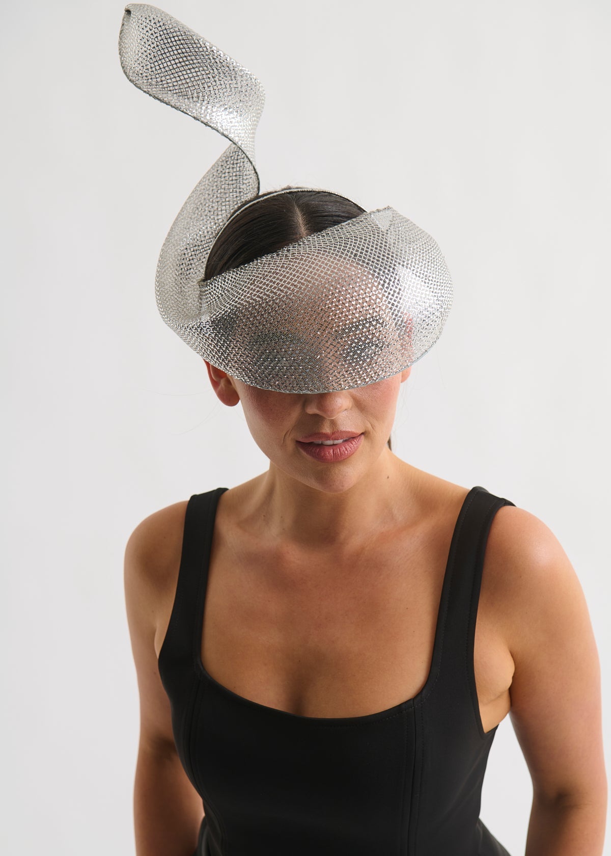 Woman wearing a silver swirl headpiece and a black dress against a white background