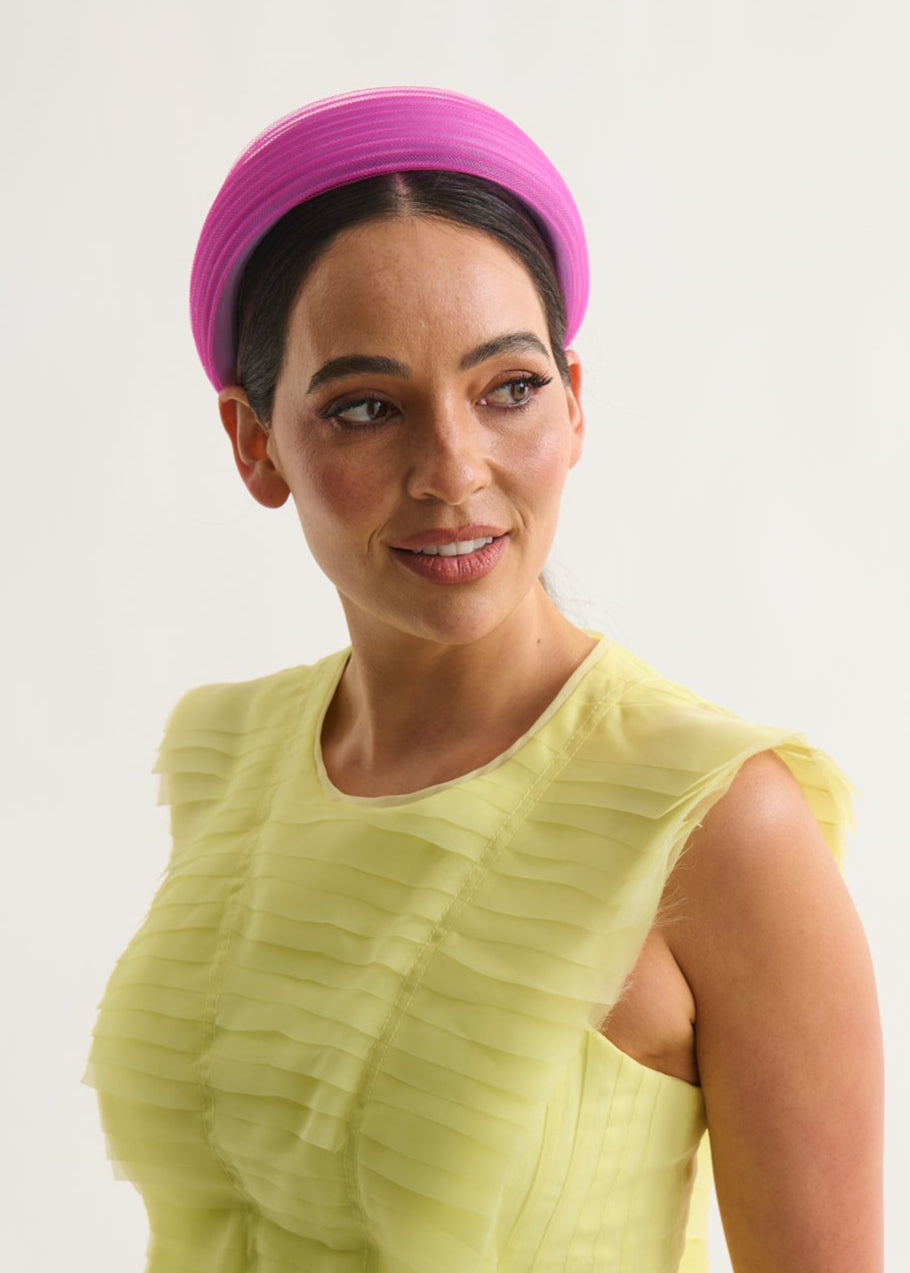 Woman wearing a yellow dress and magenta headband against a white background