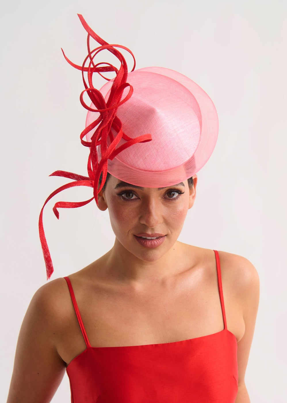 Woman wearing a pink hat with red decorative elements against a white background