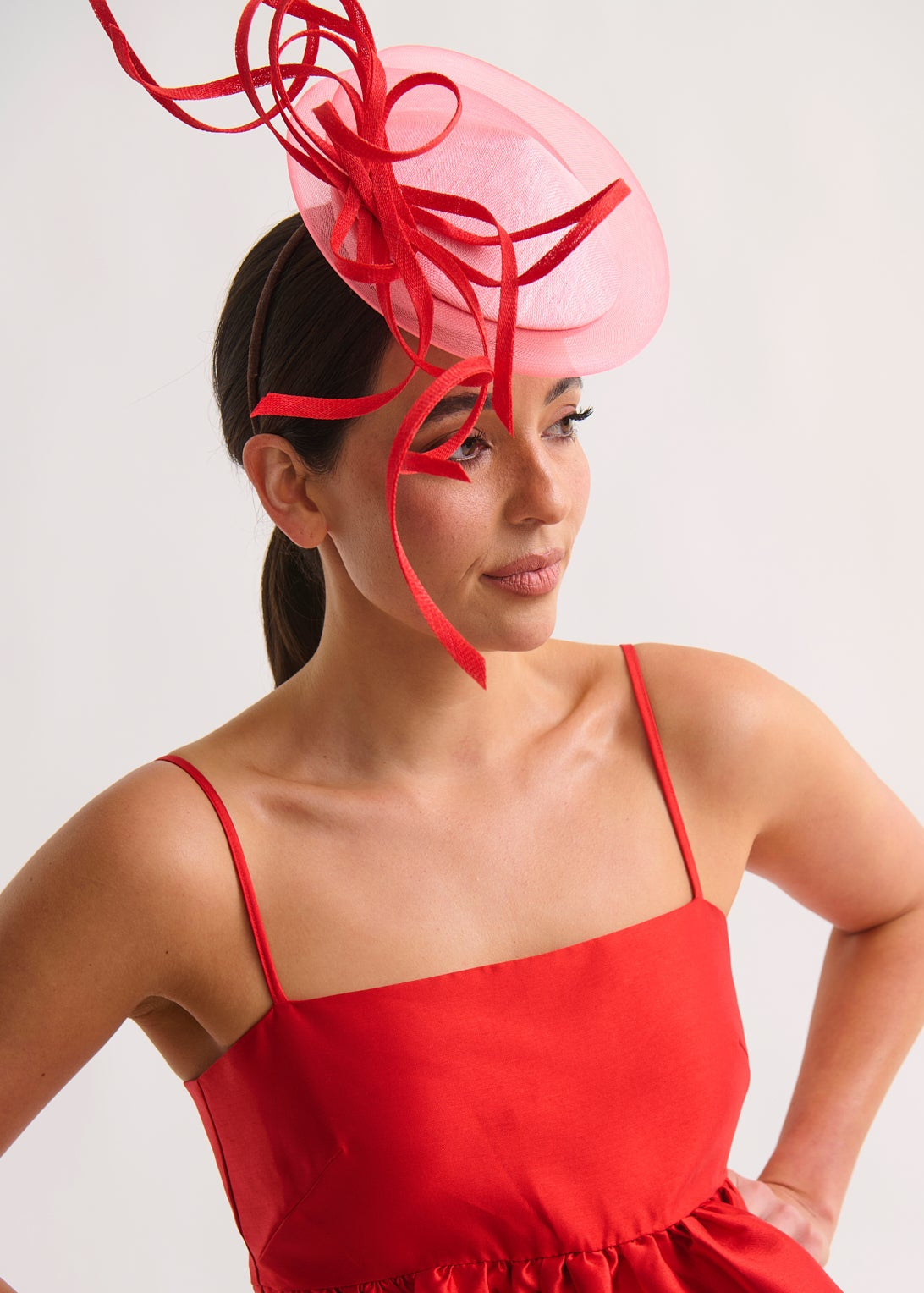 Woman wearing a red dress and large decorative headpiece against a white background