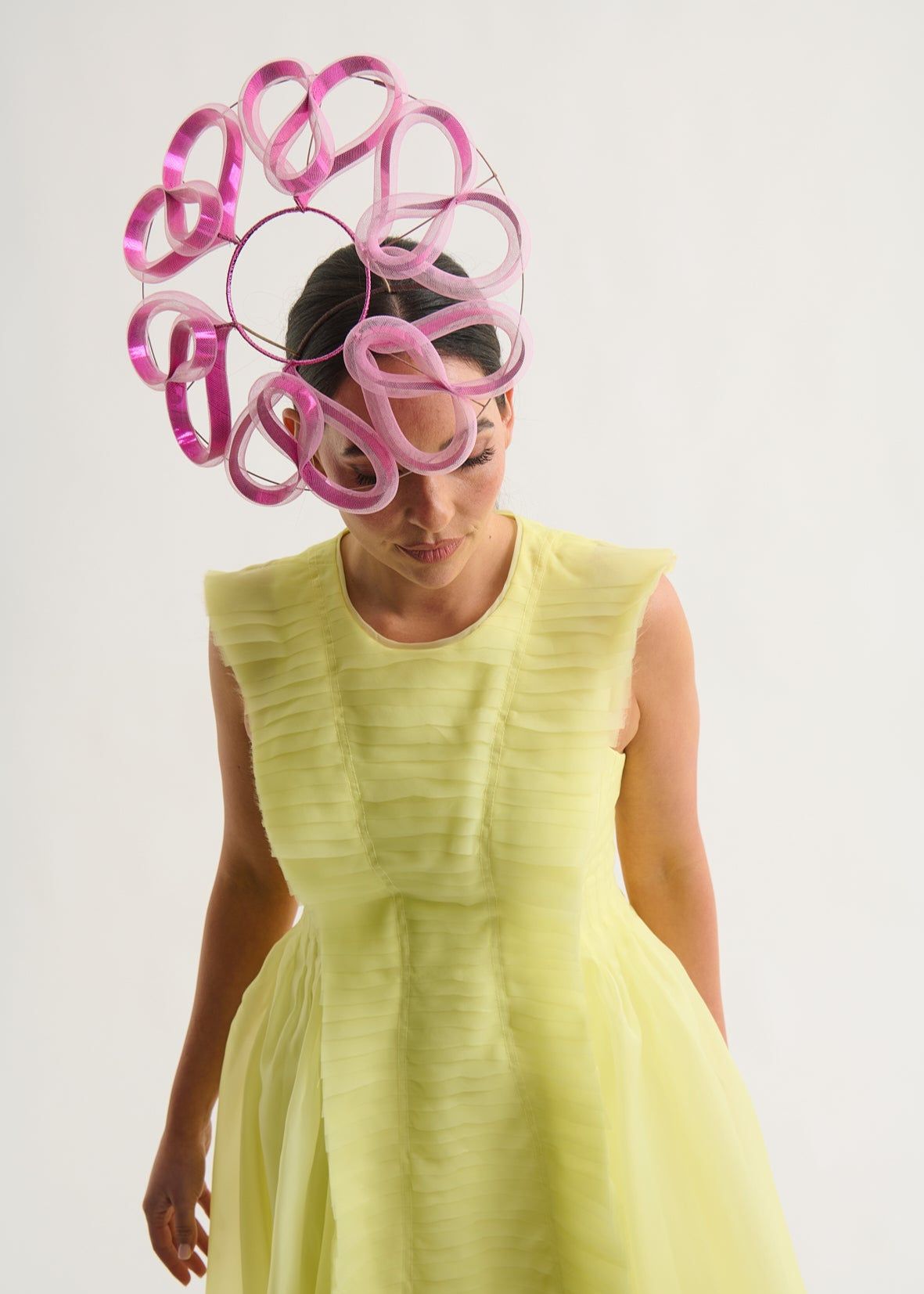 Woman wearing a futuristic headpiece with pink and magenta loops on a white background