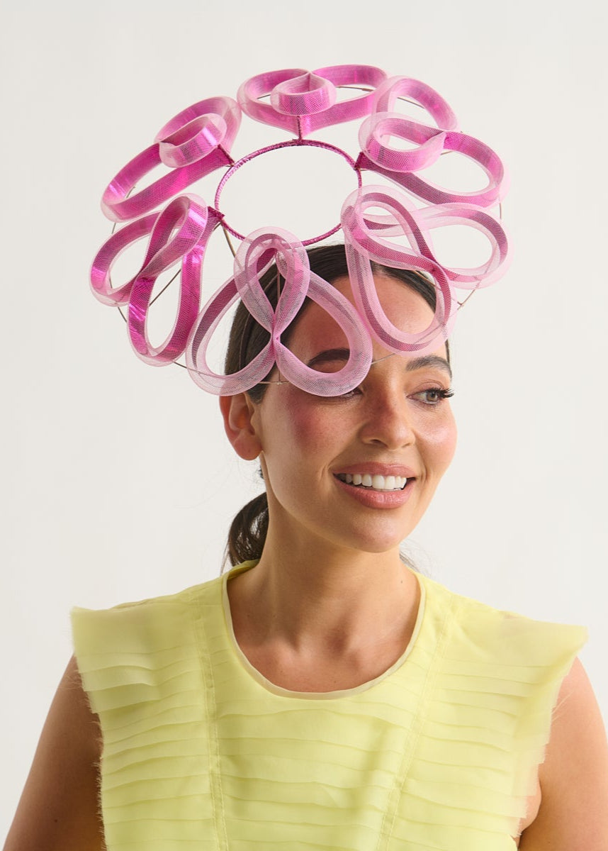 Woman wearing a pink and purple headpiece against a white background