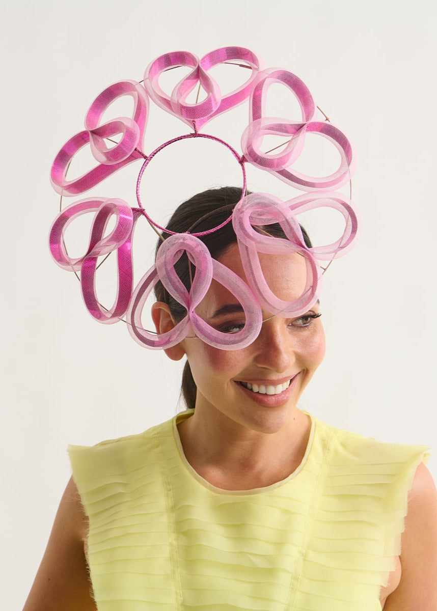 Woman wearing a pink swirl hat on a white background