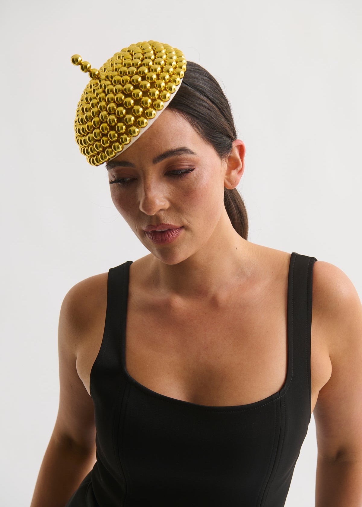 Woman wearing a black dress and a gold beaded headpiece against a white background