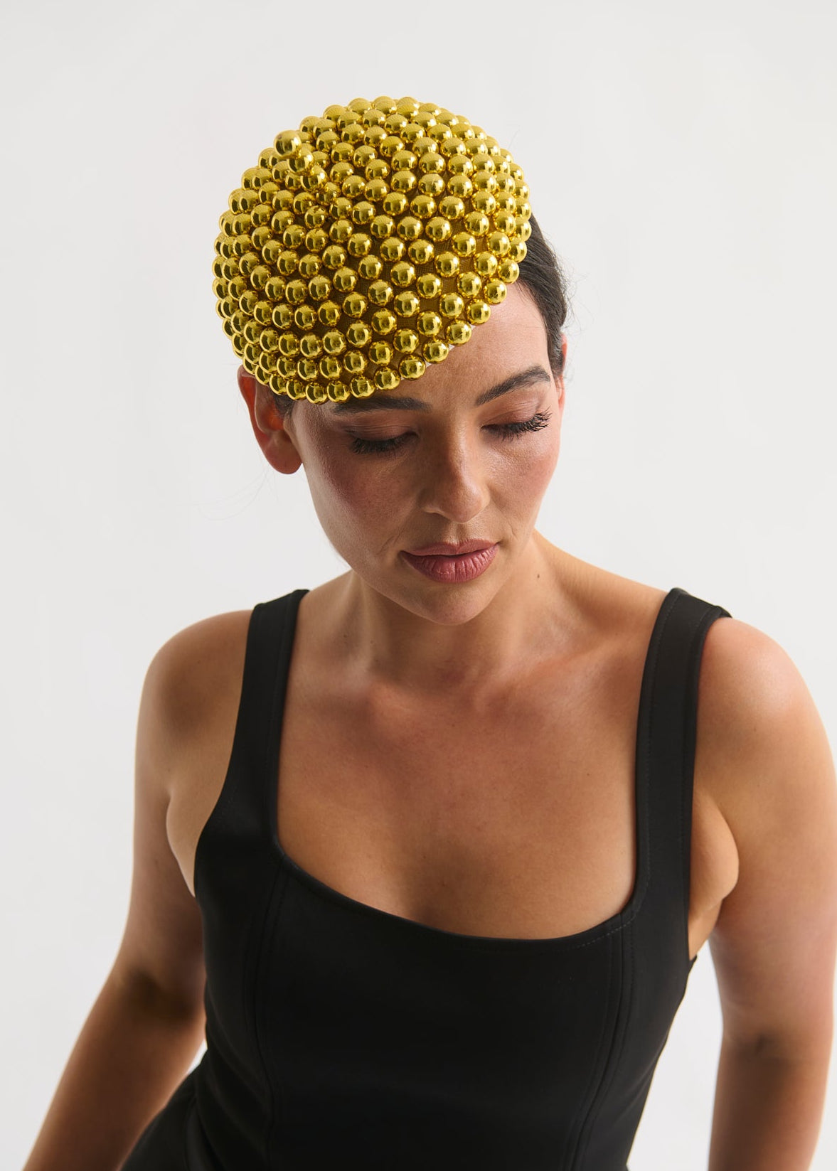 Woman wearing a black dress and gold beaded hat on a white background