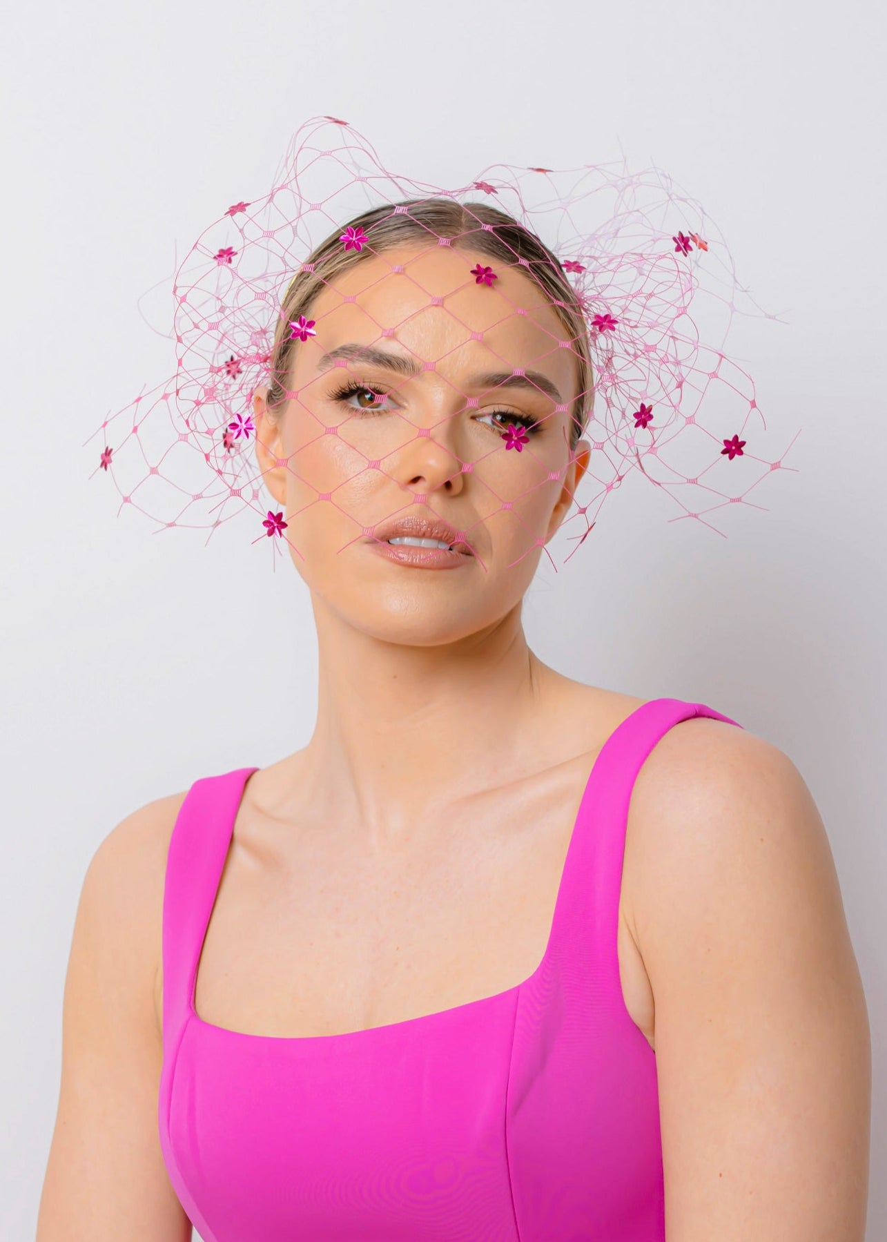 Woman wearing a bright pink dress with a white background
