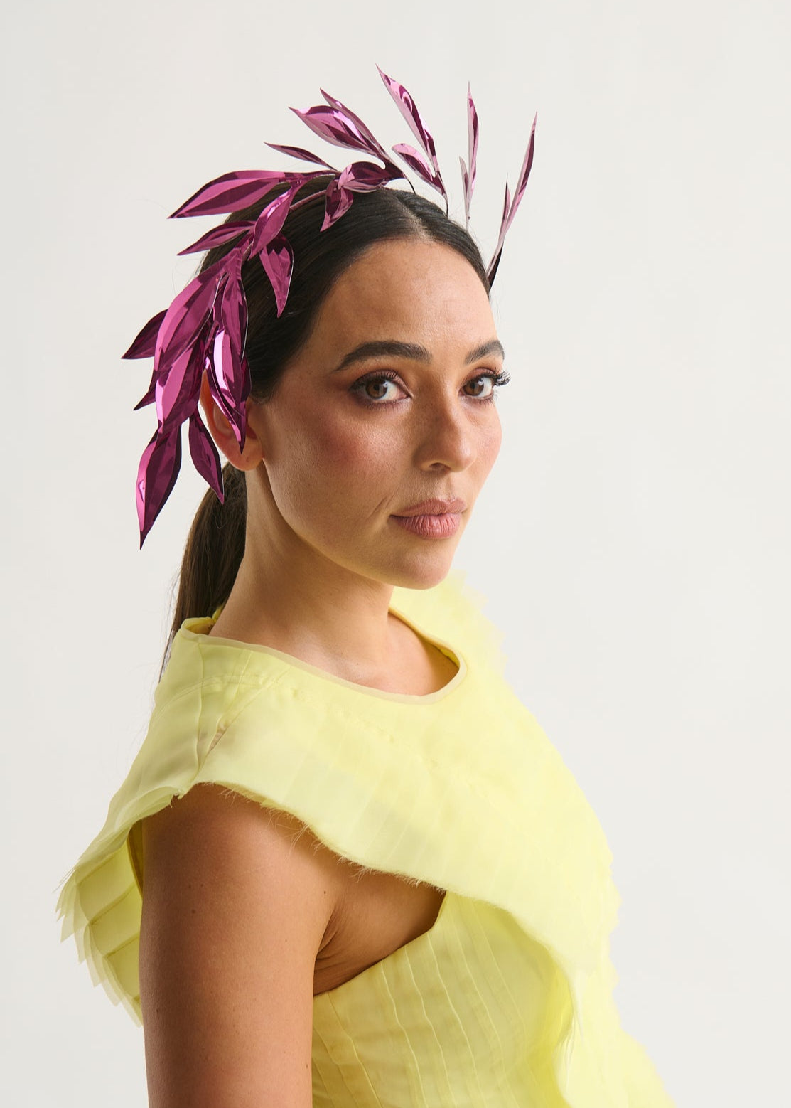 Woman wearing a leaf headpiece and yellow dress with a white background