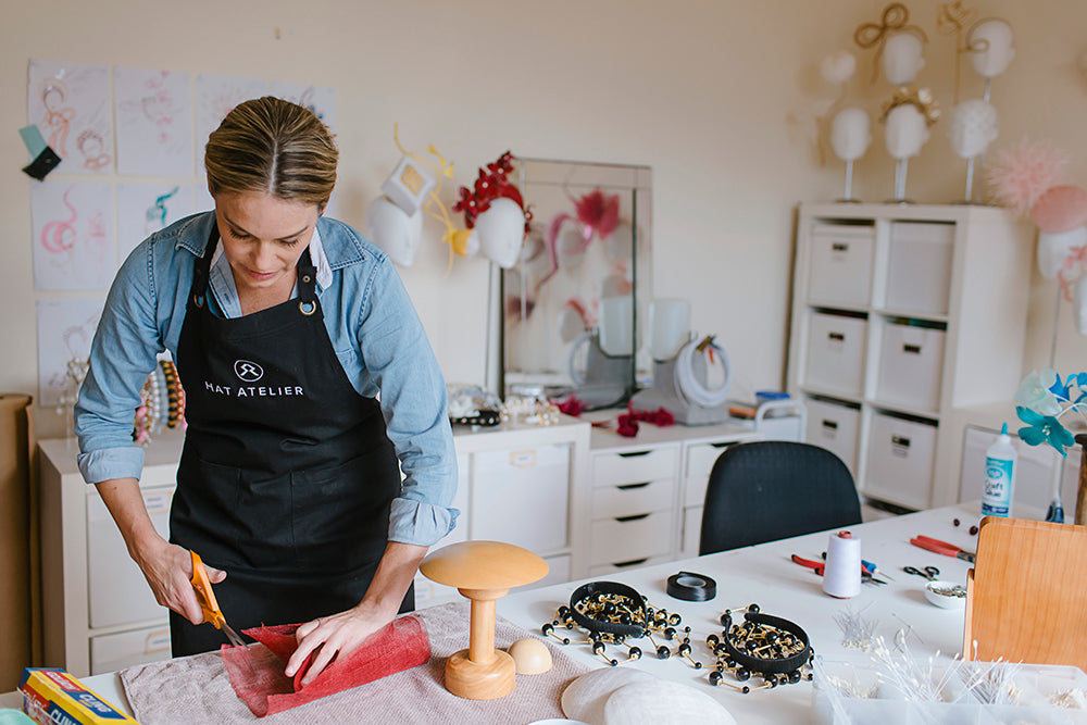 Rebecca Share Milliner cutting red sinamay in her Millinery Studio