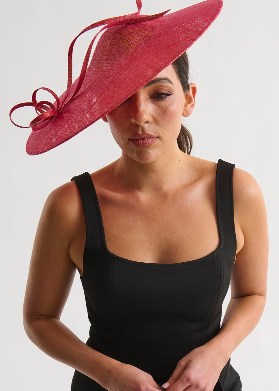 Woman wearing a black dress and red hat against a white background