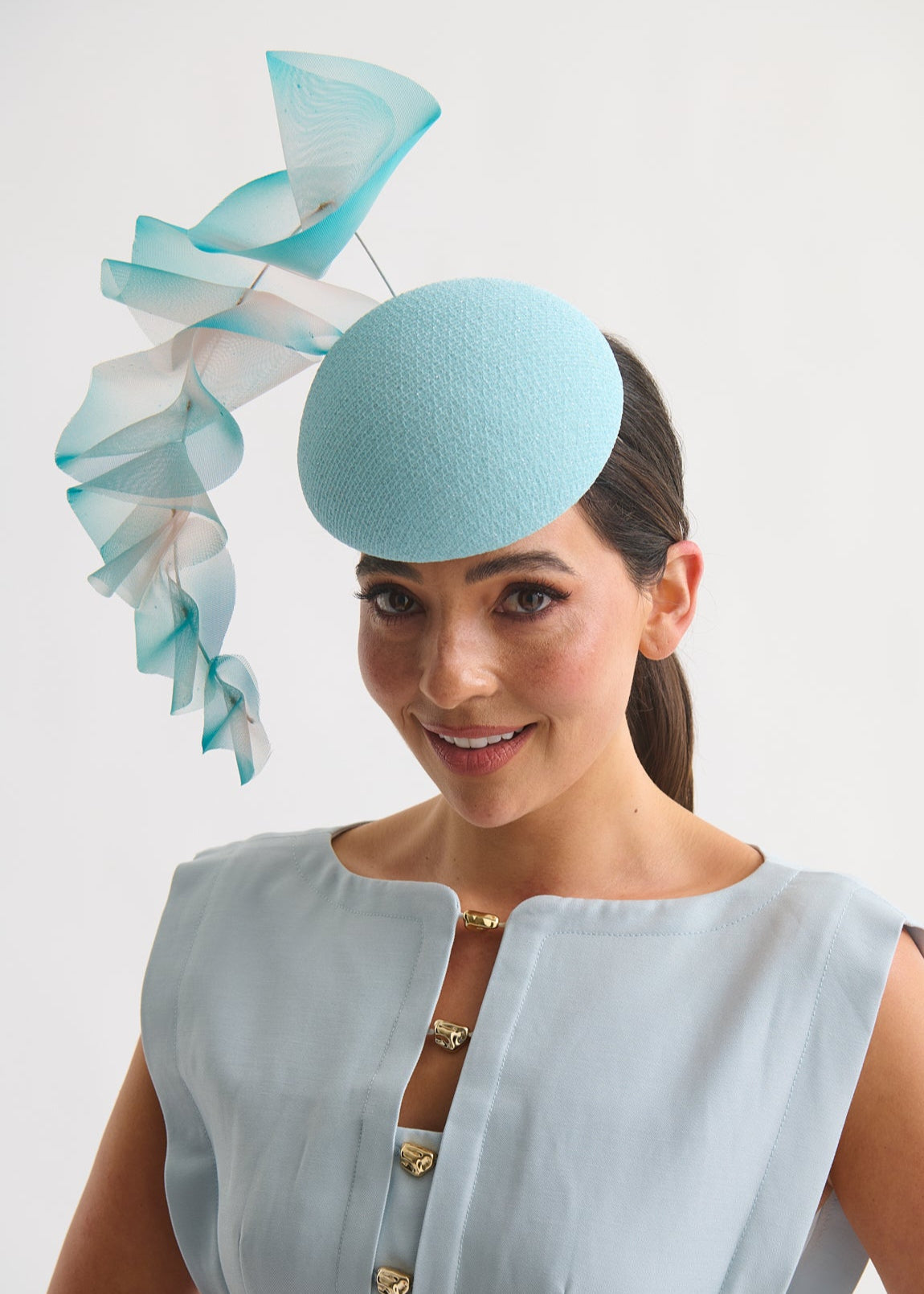 Woman wearing a light blue hat with decorative ruffles on a white background