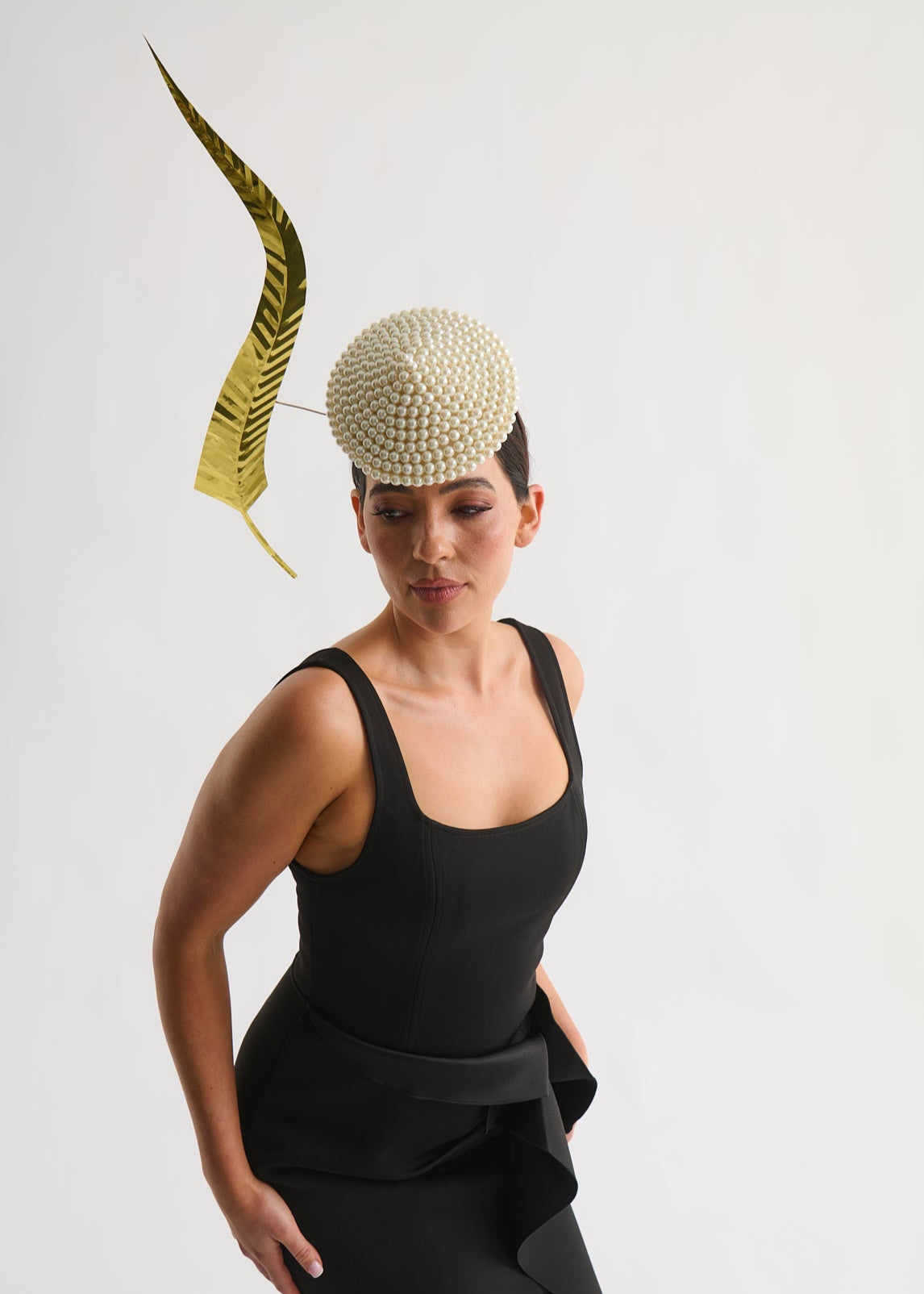 Woman wearing a black dress with a decorative headpiece against a white background