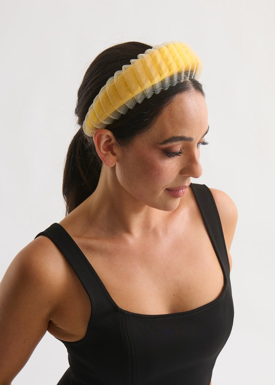 Woman wearing a yellow headband against a white background