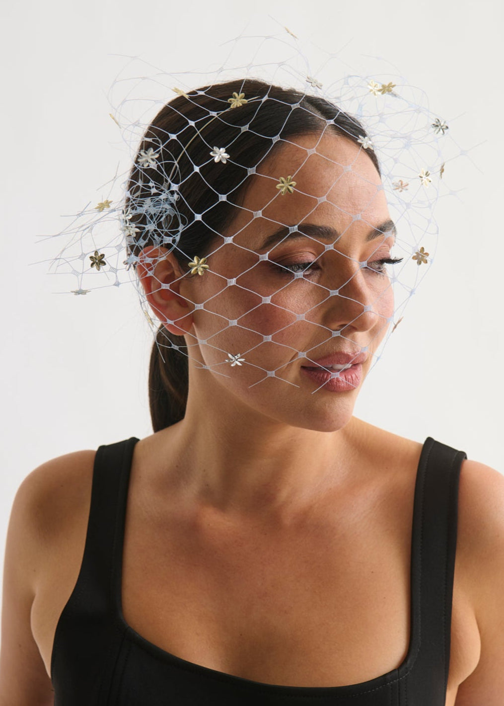Woman wearing a black dress with a birdcage veil against a white background