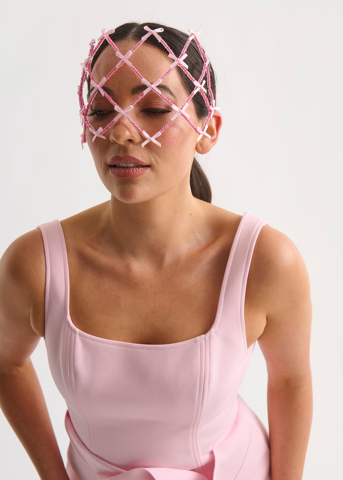 Woman wearing a pink headpiece against a white background