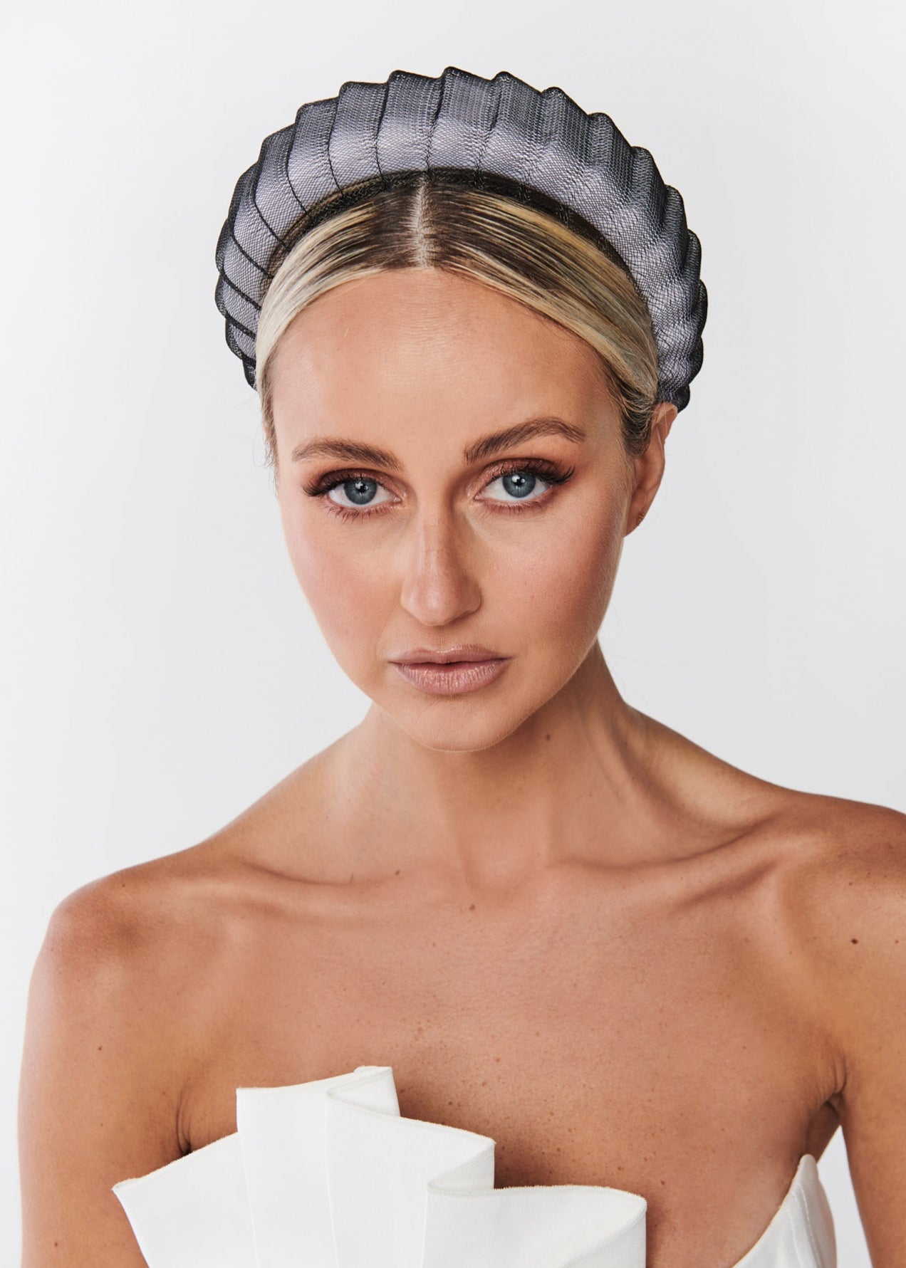 Woman wearing a black headband with ruffled edges on a white background