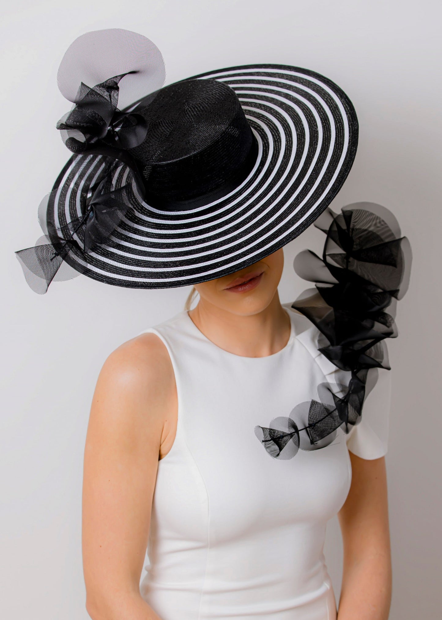 Person wearing a black and white striped hat with decorative elements on a plain background