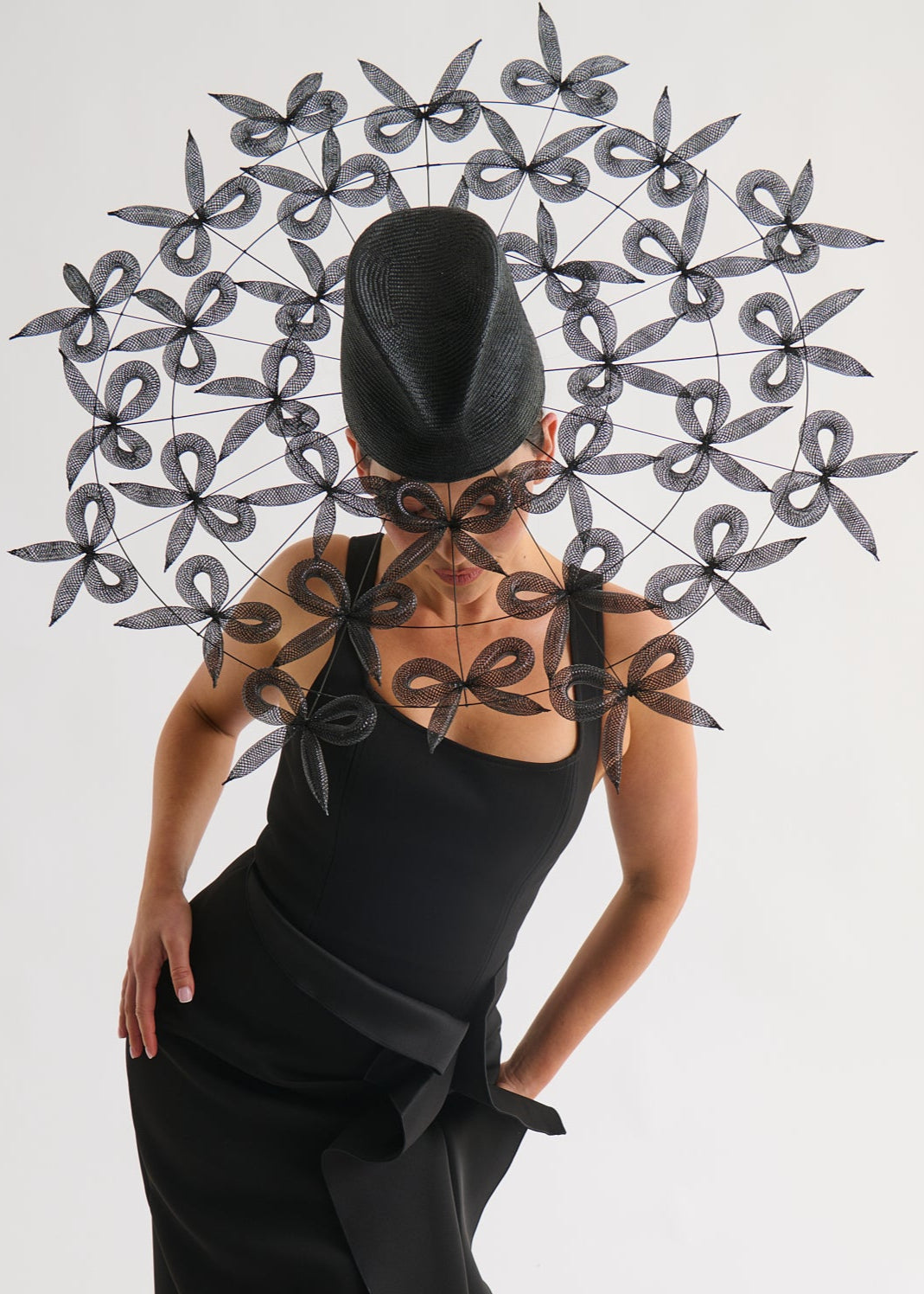 Person wearing a black dress with a matching headpiece against a white background