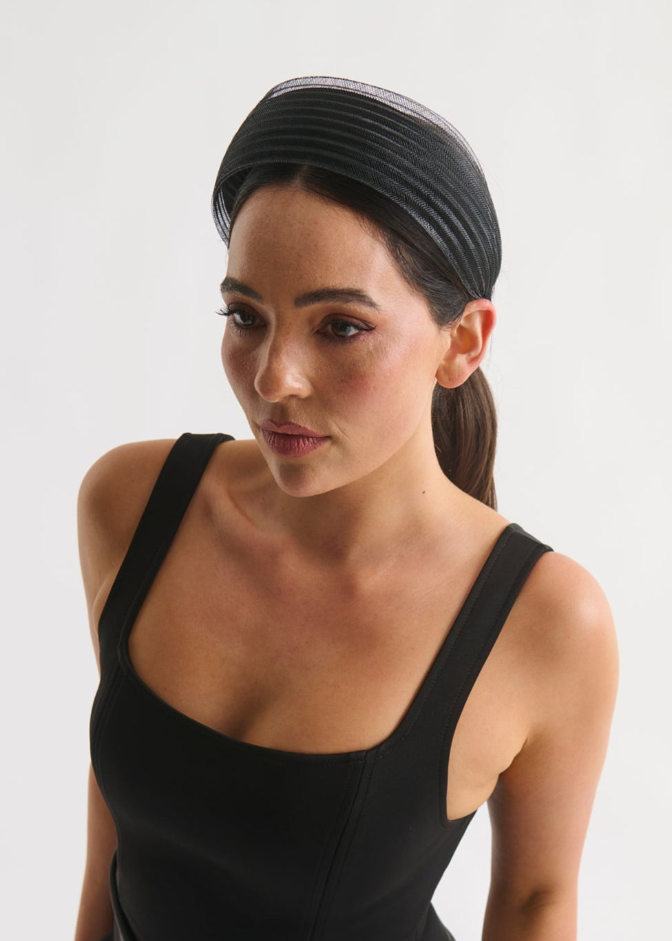 Woman wearing a black dress and headband against a white background