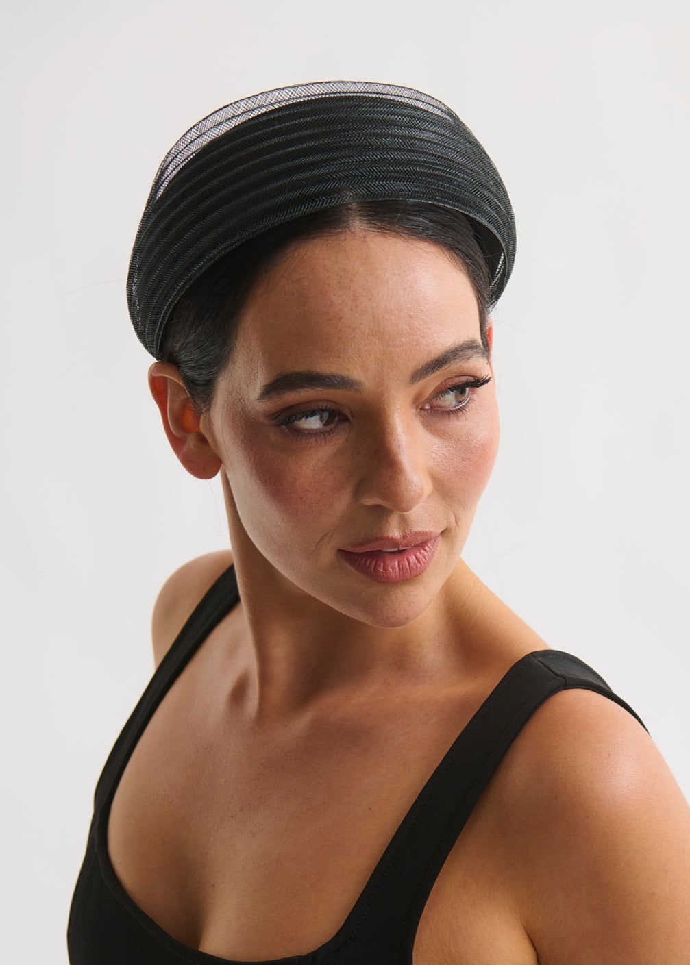 Woman wearing a black headband and black top against a white background