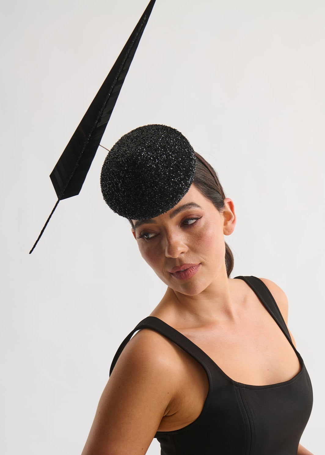 Woman wearing a black hat with a decorative element on a white background