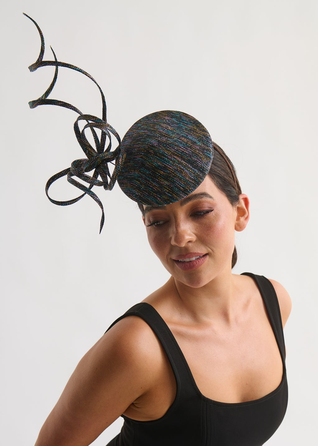 Woman wearing a decorative hat with a large bow on a plain background
