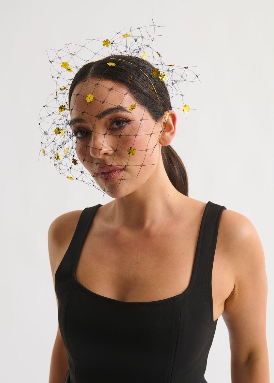 Woman wearing a black dress with a decorative headpiece against a white background