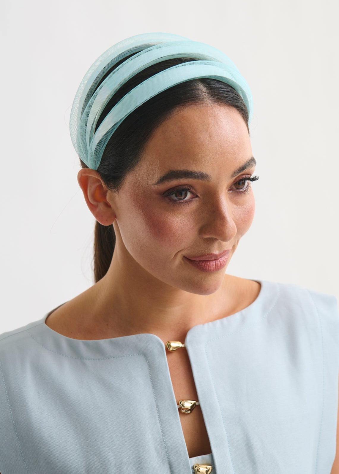 Woman wearing a light blue headband against a white background