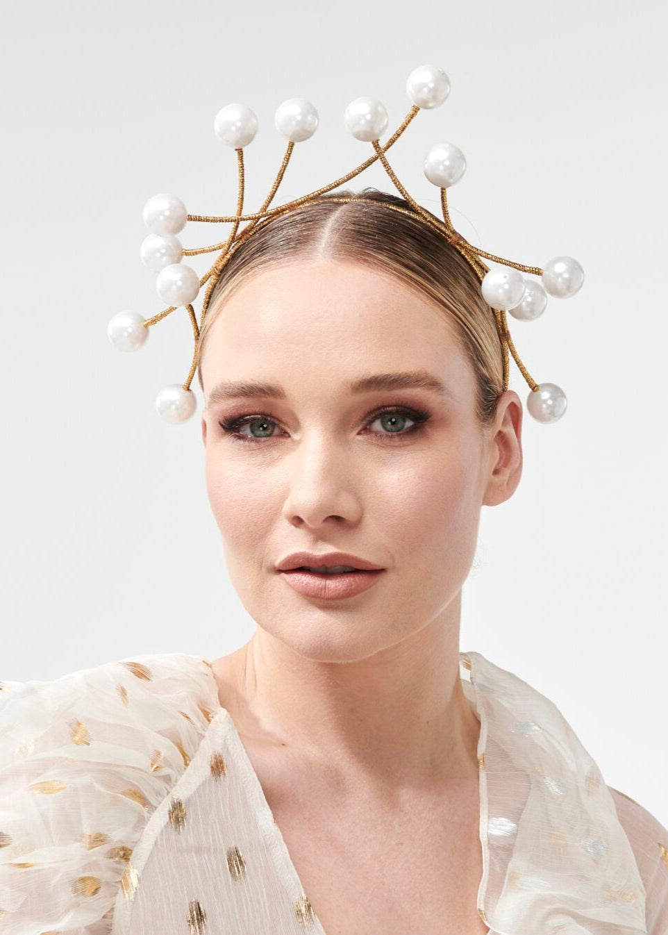 Woman wearing a decorative headpiece with pearls on a plain background