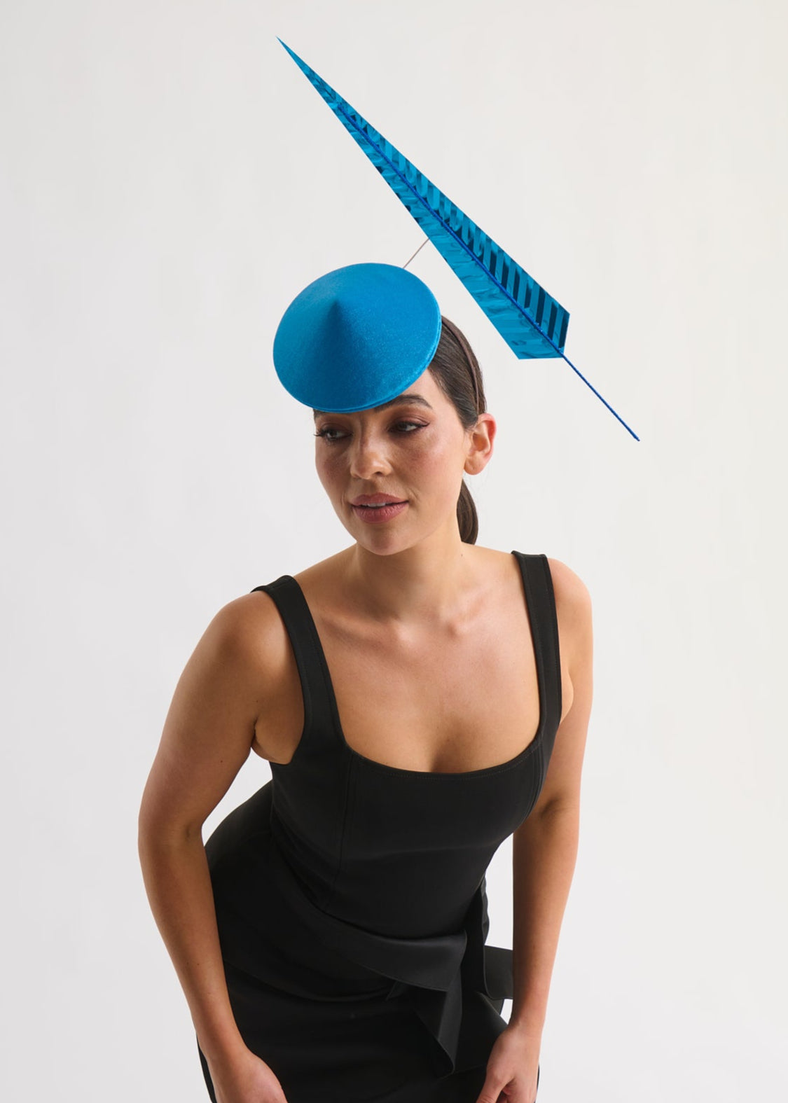 Woman wearing a black dress with a blue hat on a white background