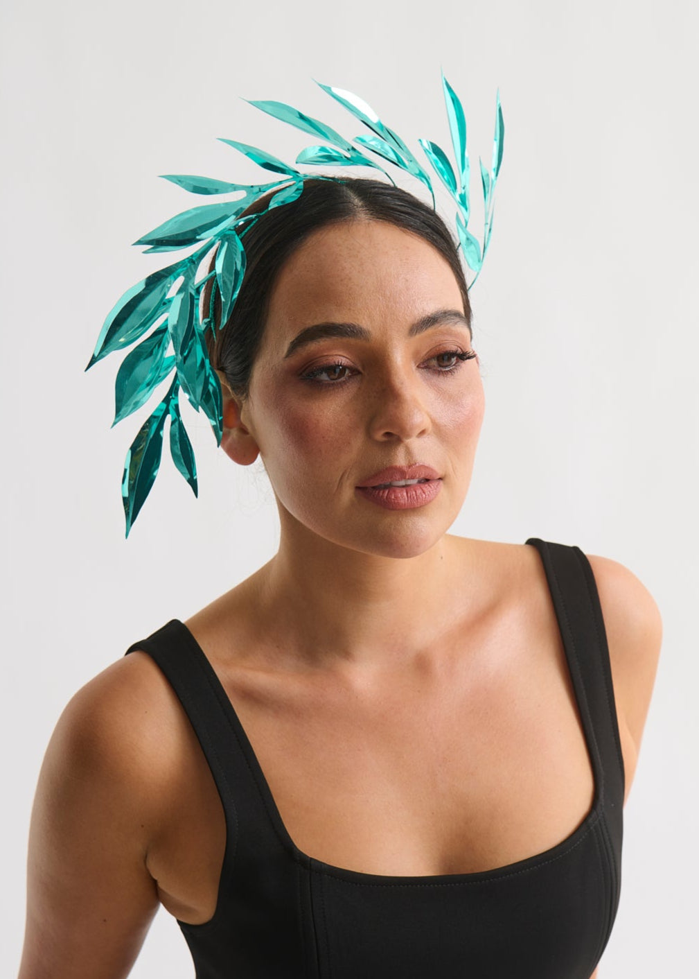 Woman wearing a leaf headpiece and black dress with a white background