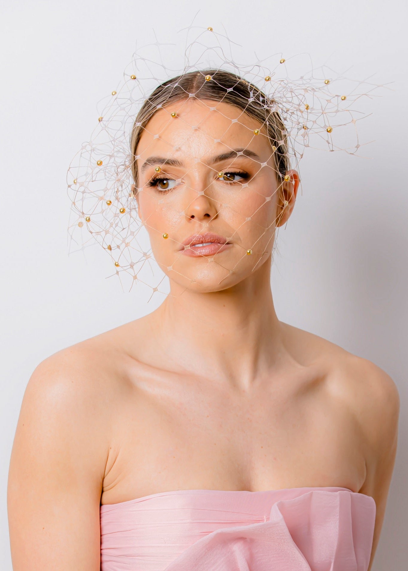 Woman wearing a strapless pink dress against a plain background