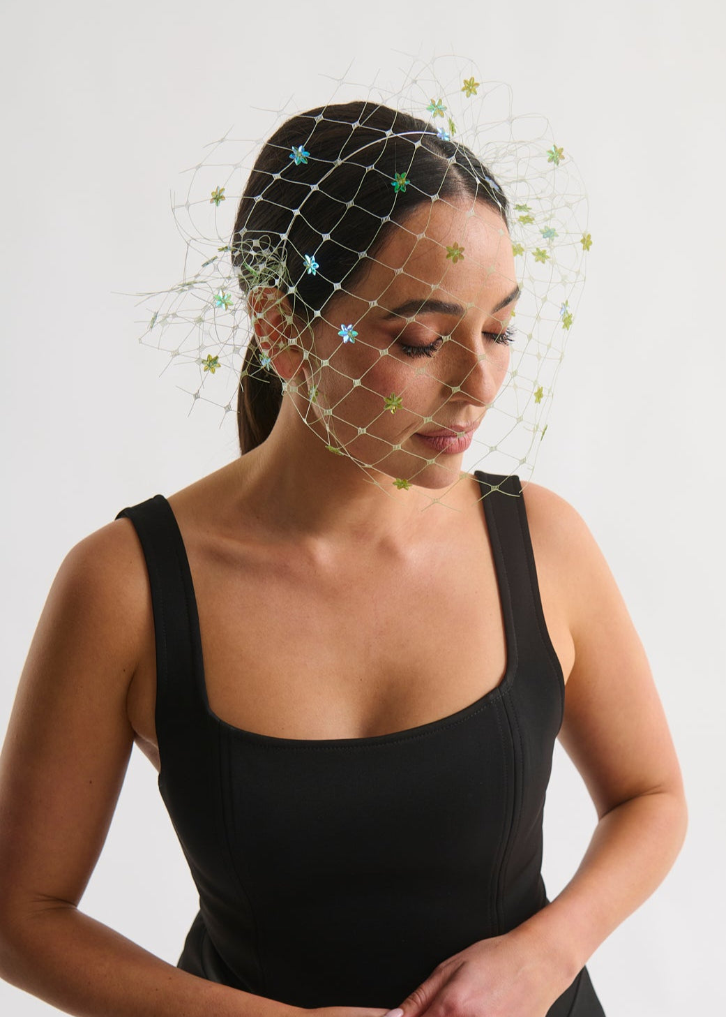 Woman wearing a black sleeveless top with a decorative headpiece on a white background