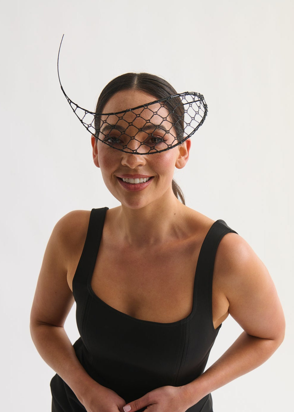 Woman wearing a black dress and headpiece against a white background