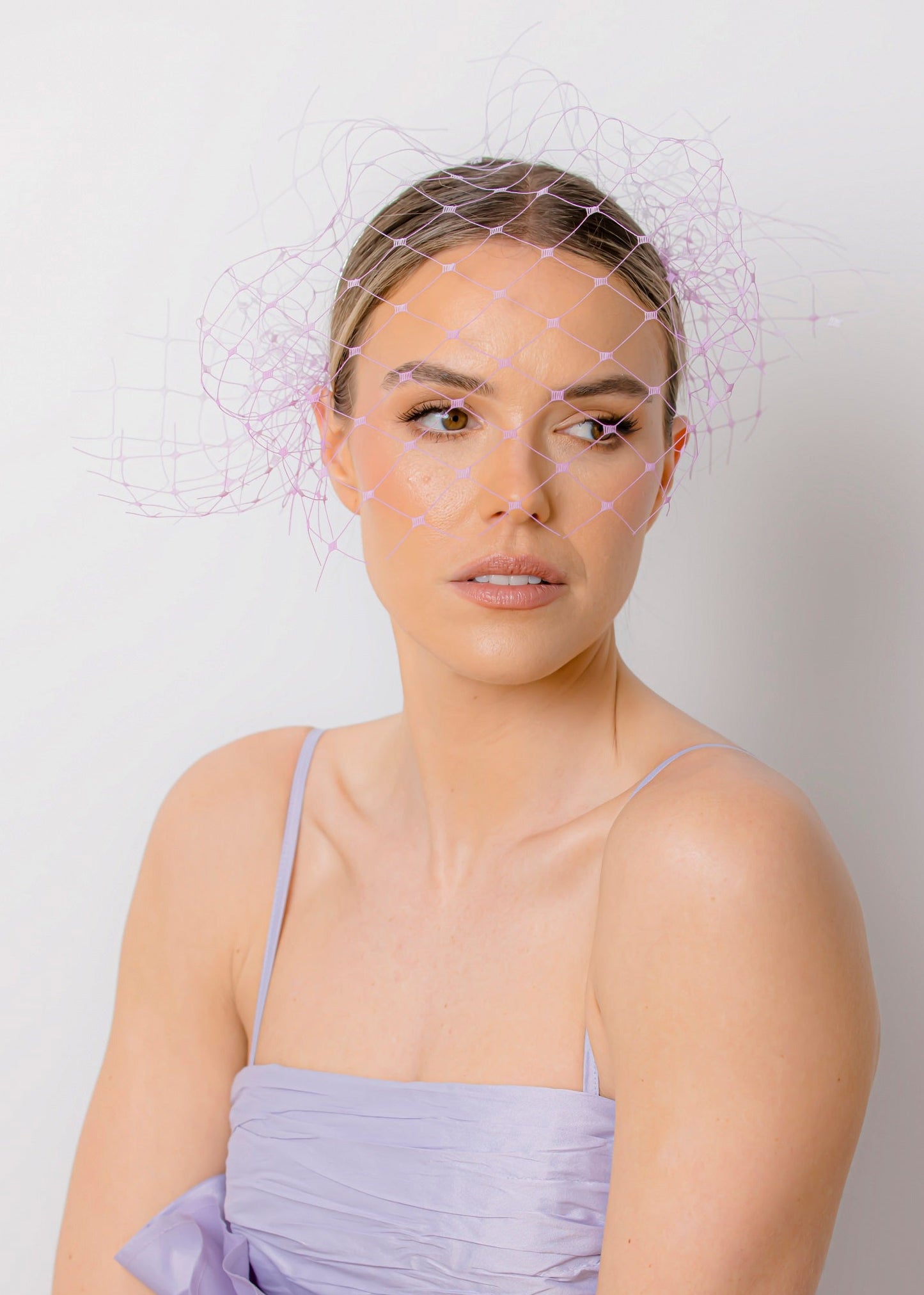 Woman wearing a light purple dress with ruffled details against a plain background