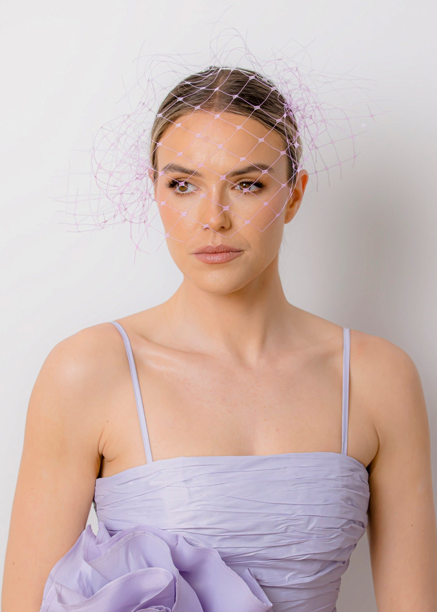 Woman wearing a light purple dress with floral details against a plain background