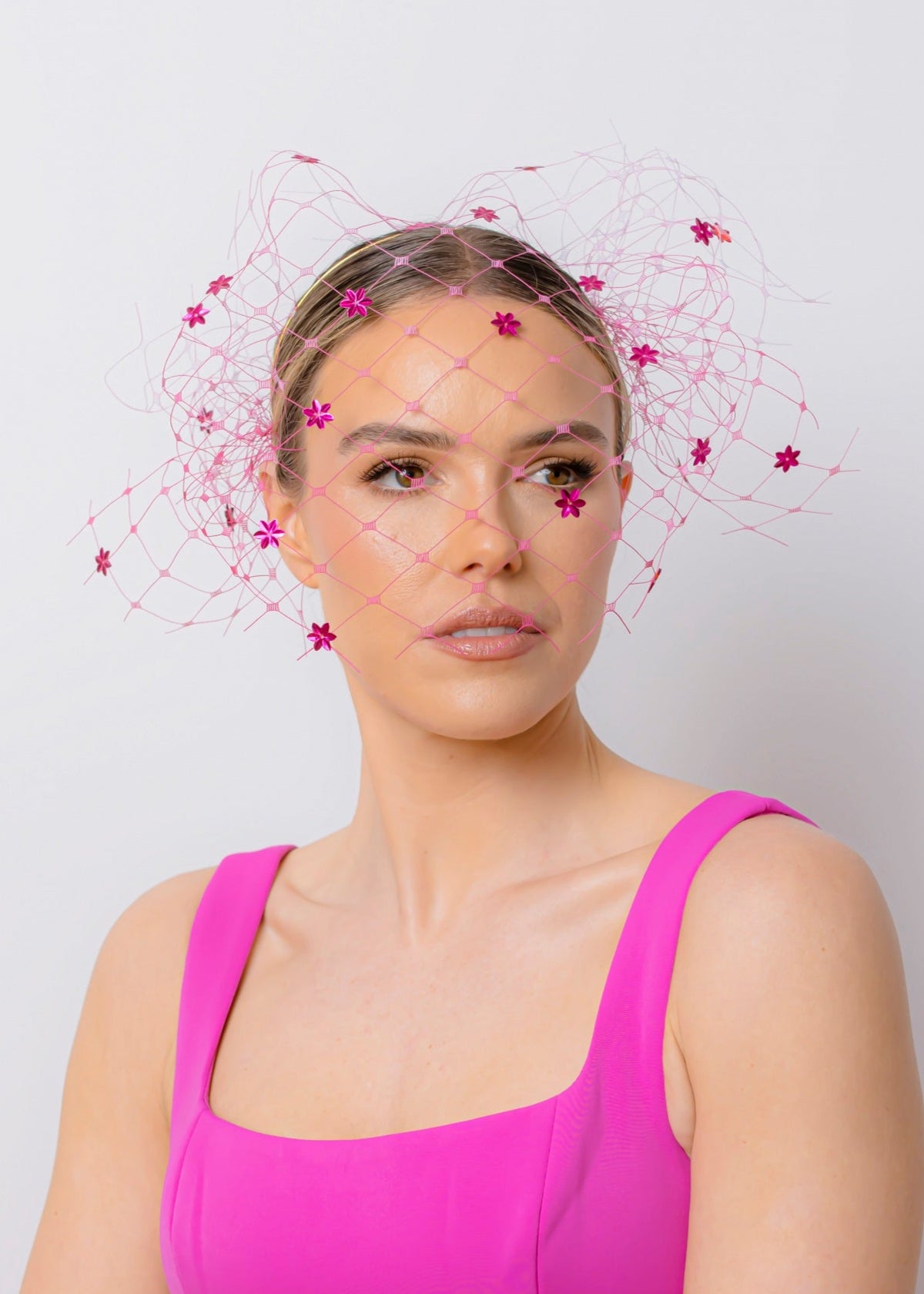 Woman wearing a bright pink dress with a white background