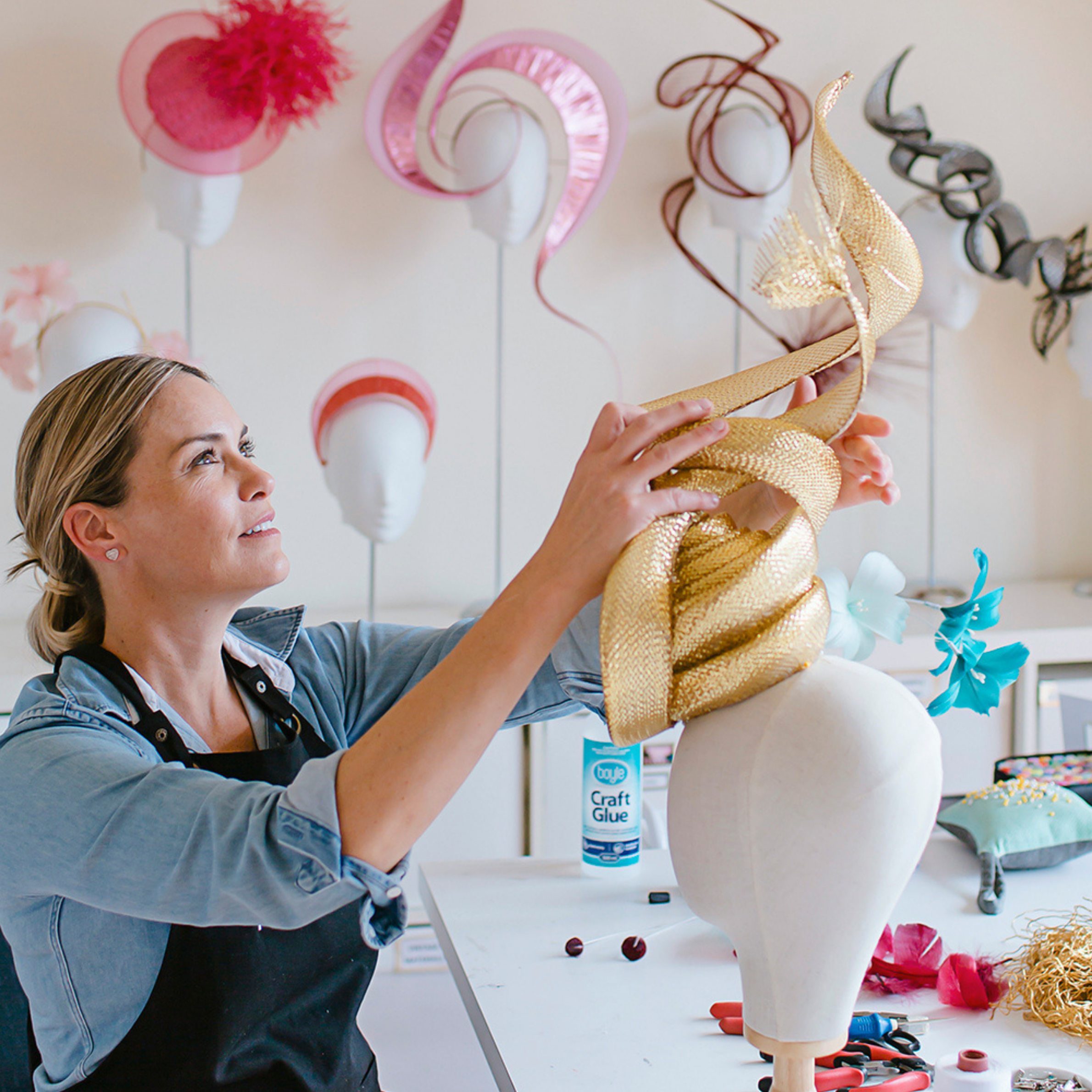 Milliner Rebecca Share arranging elements of a designer headwear on a hat block