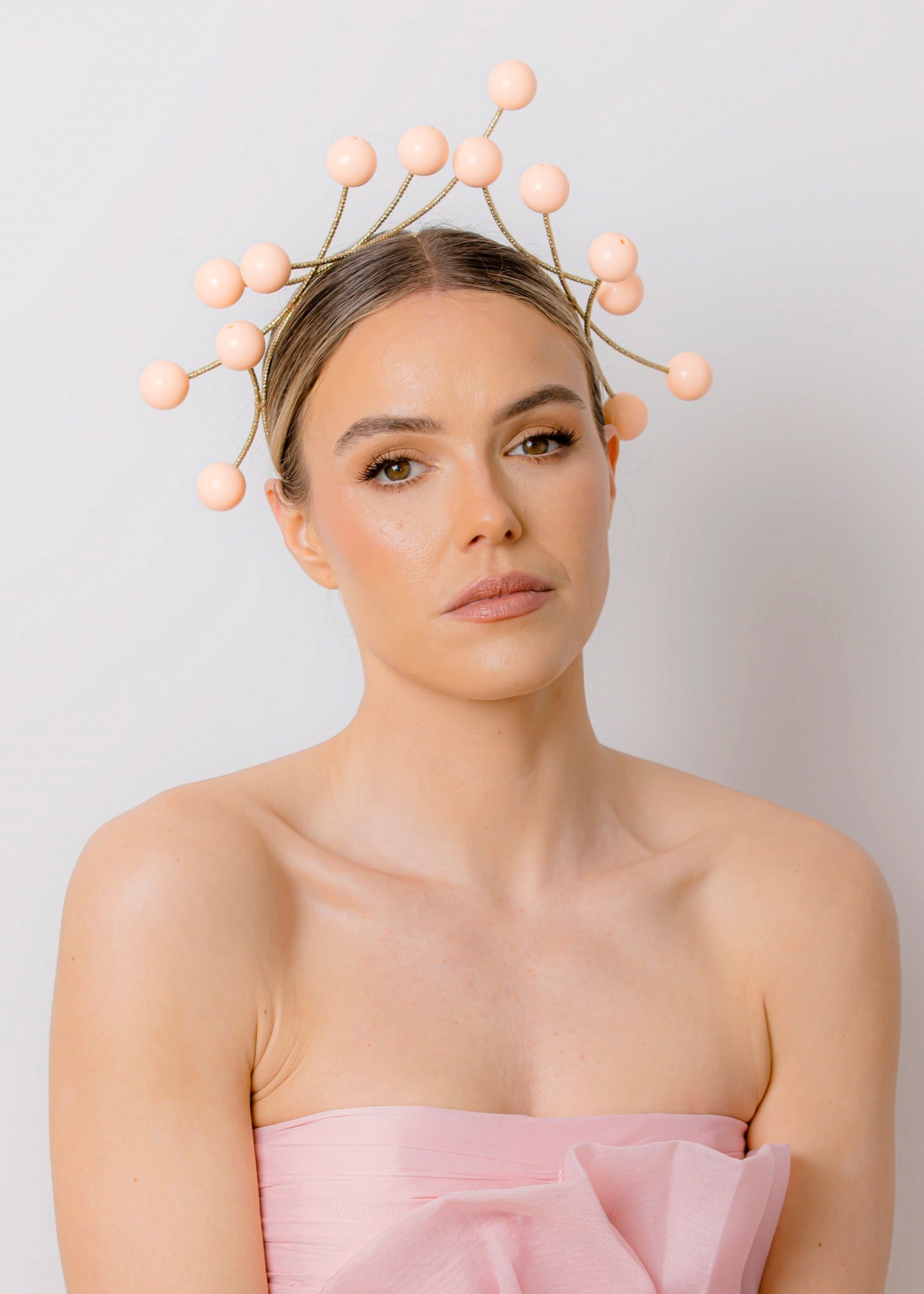 Woman wearing a strapless pink dress and beaded headpiece against a plain background
