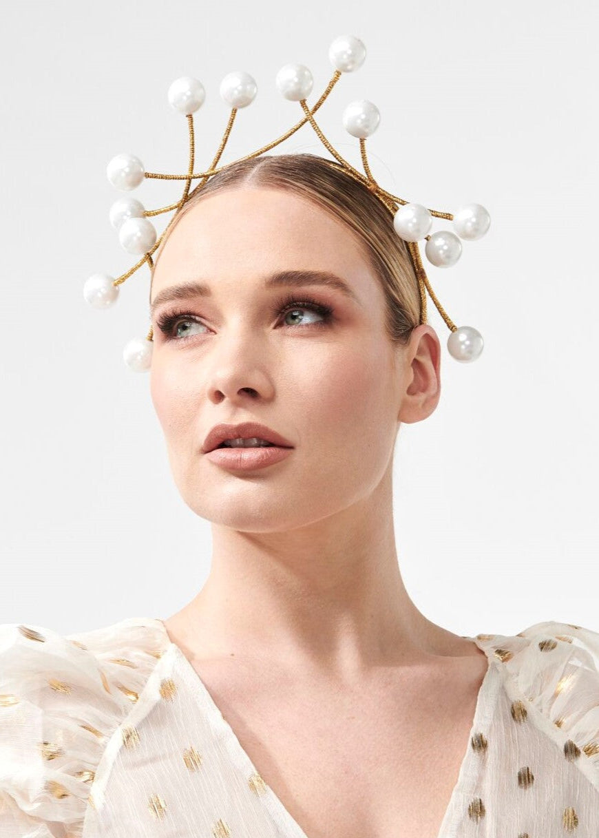 Woman wearing a decorative headpiece with pearls on a light background