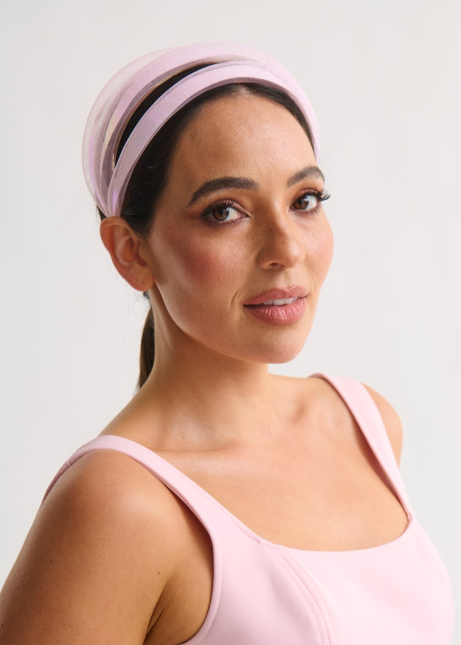 Woman wearing a pink dress and headband against a white background