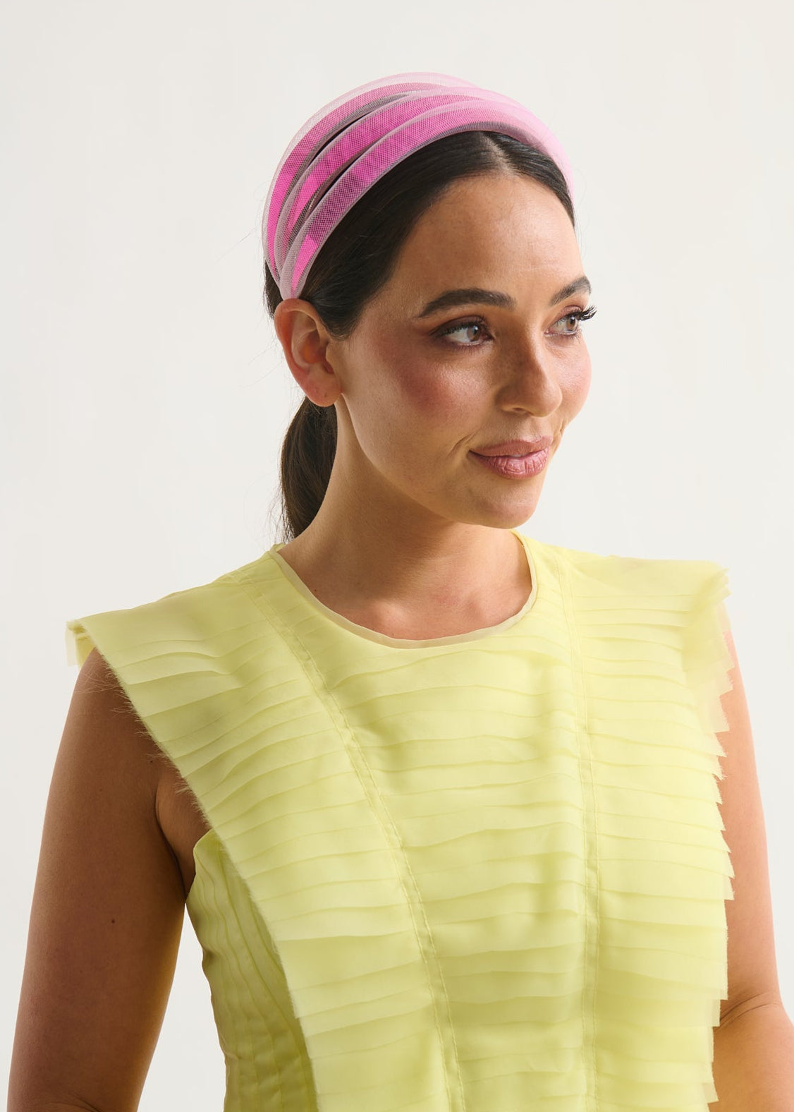 Woman wearing a pink headband and a yellow dress against a white background