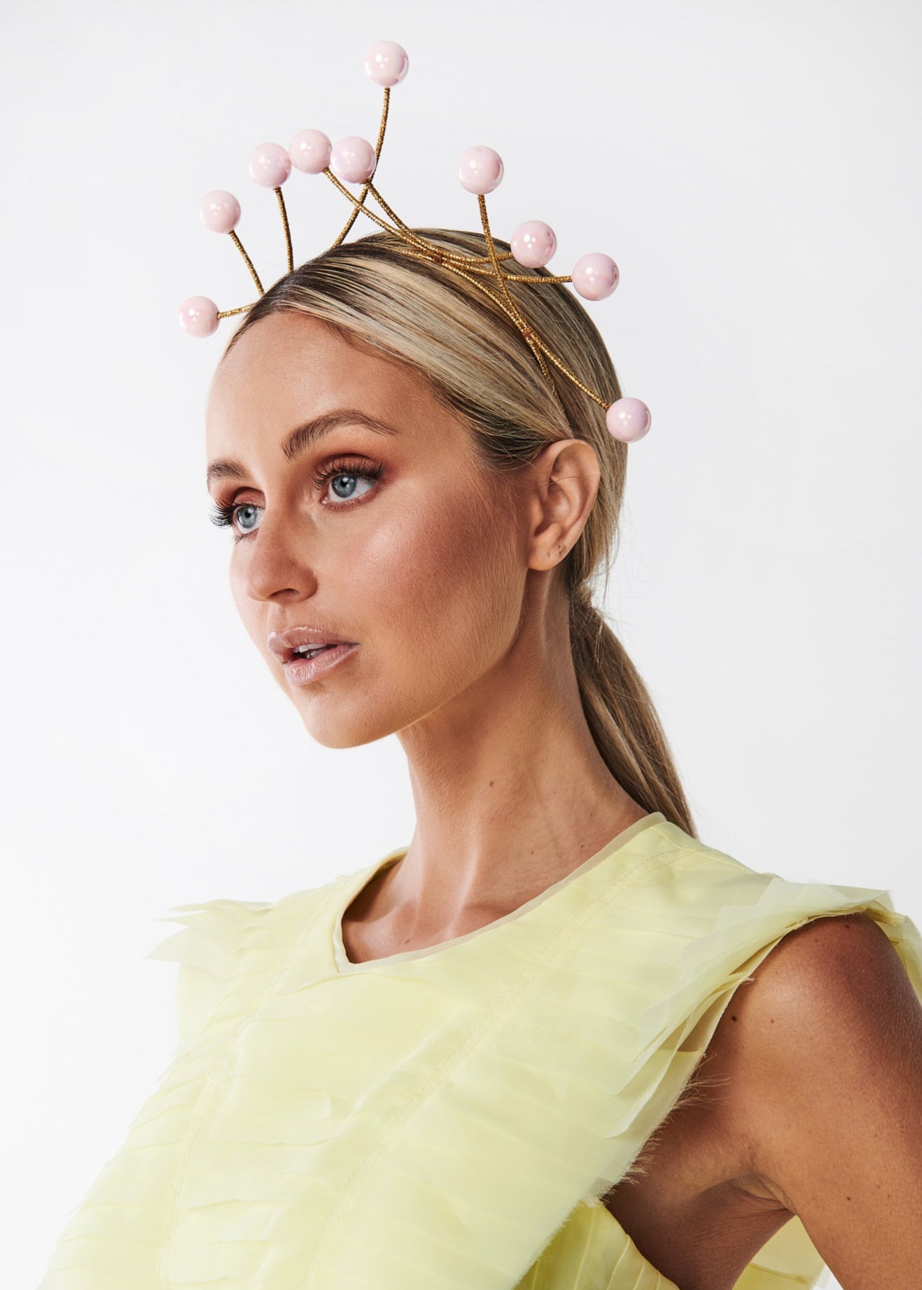 Woman wearing a decorative headpiece with pink elements on a white background