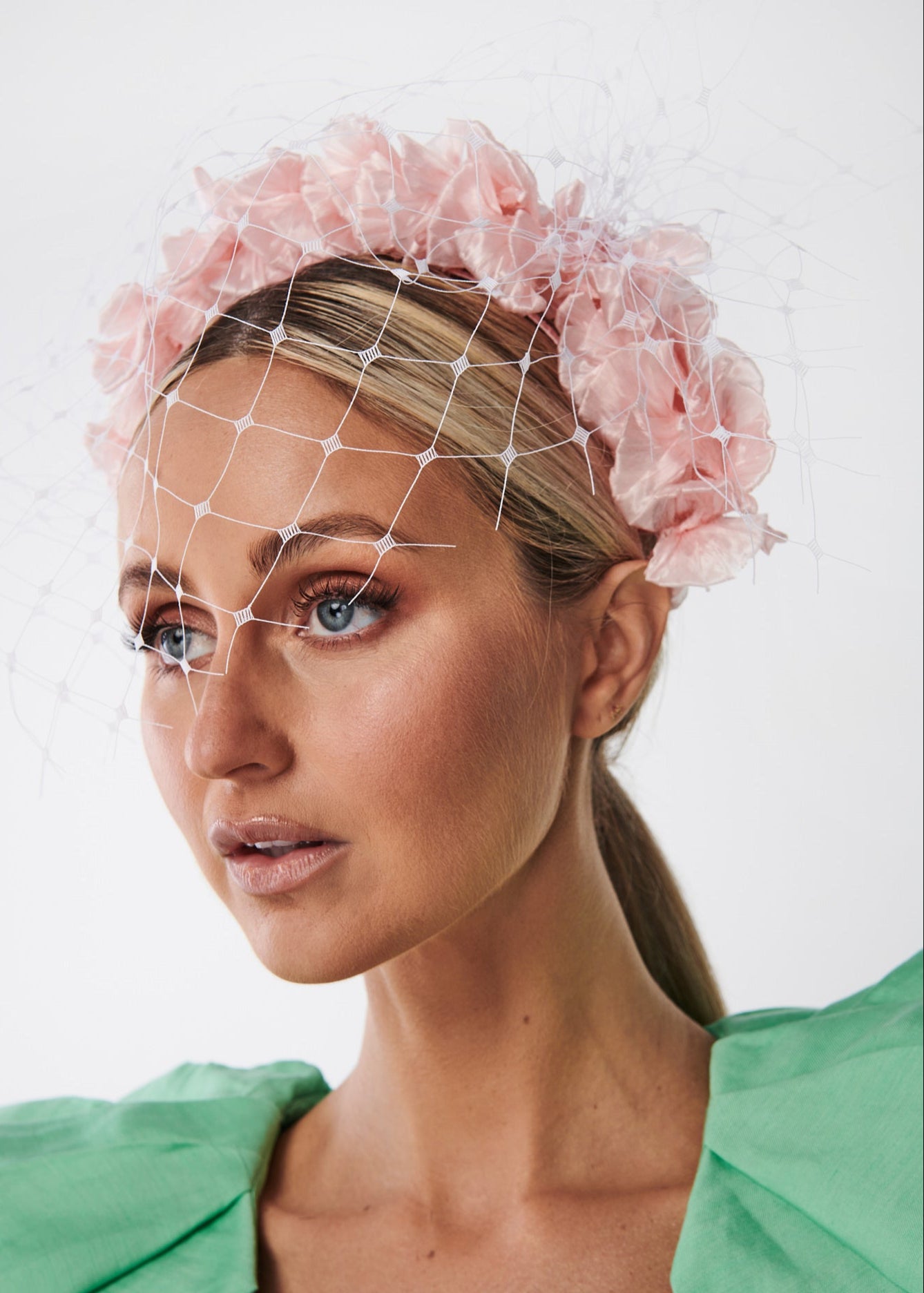 Woman wearing a pink floral headband with a white background
