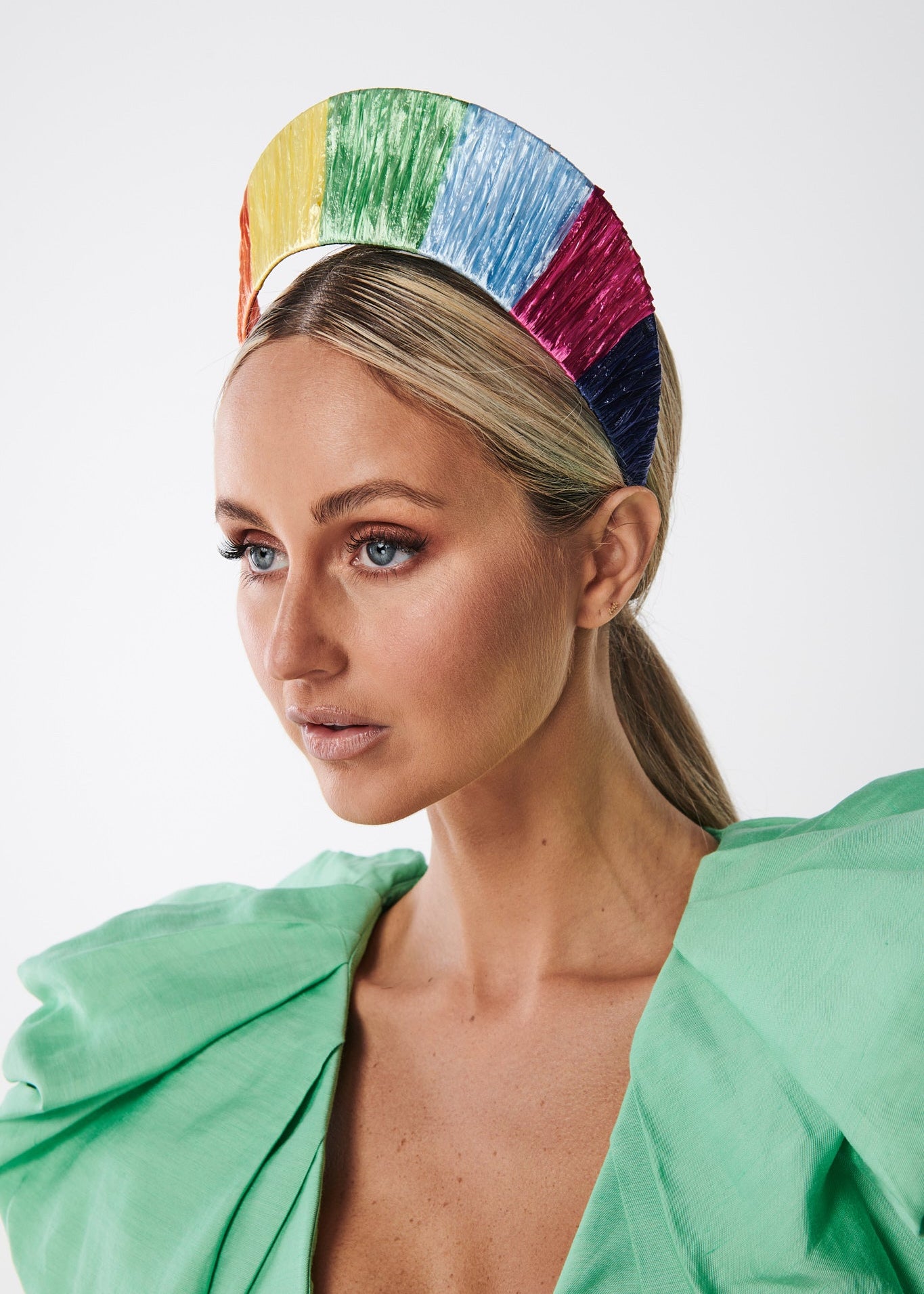 Woman wearing a colorful rainbow headband against a white background