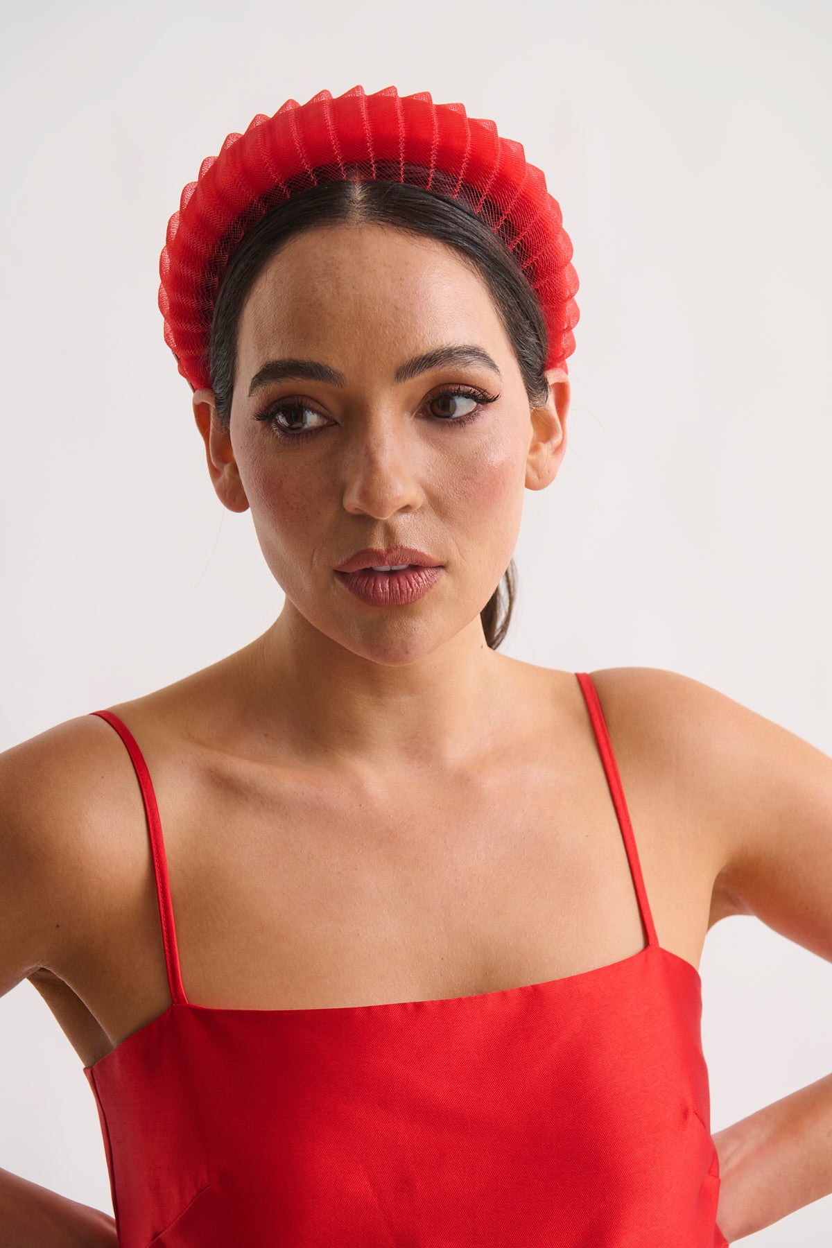 Woman wearing a red dress and headband against a white background
